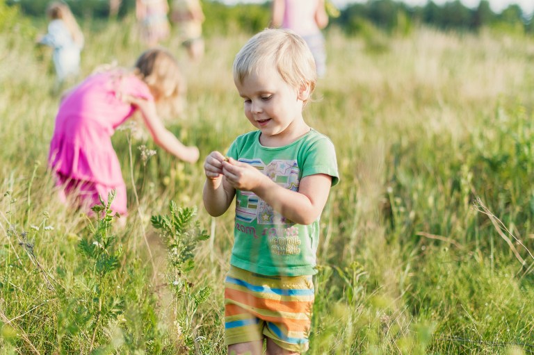 young children playing with grass in a field