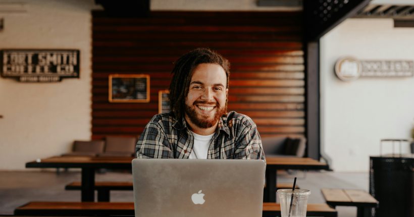 man smiling behind laptop